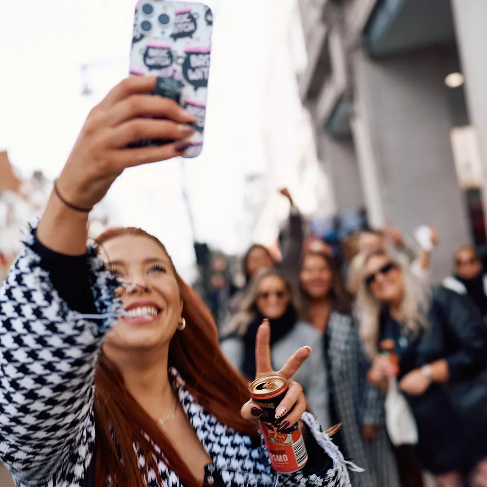 woman-taking-a-crowd-selfie-holding-a-can